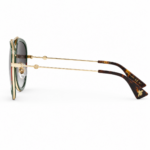 Lentes de sol Gucci estilo aviador en vista lateral, con estructura dorada, terminales carey y detalles de marca sobre fondo blanco.