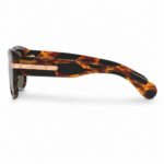 Lentes de sol Gucci con montura carey en vista lateral, cristales oscuros y detalle metálico con logo sobre fondo blanco.
