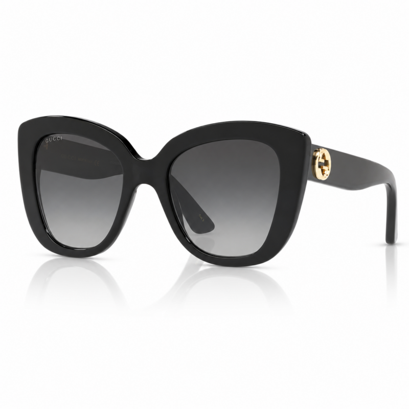 Lentes de sol Gucci negros en vista principal, con montura oversized, cristales degradados grises y logo GG dorado en la patilla sobre fondo blanco.